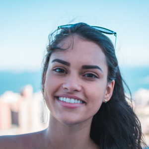 A smiling customer with long dark hair, expressing satisfaction with Heavenly Care skincare products in an outdoor setting.